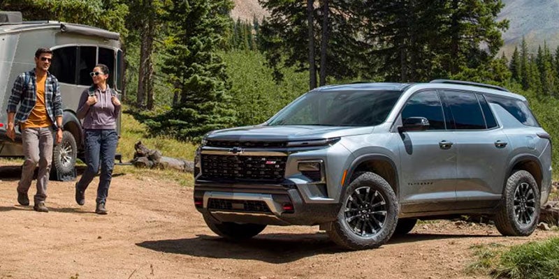 GMC Traverse parked in the forest as two people come over to get more equipment out of the vehicle