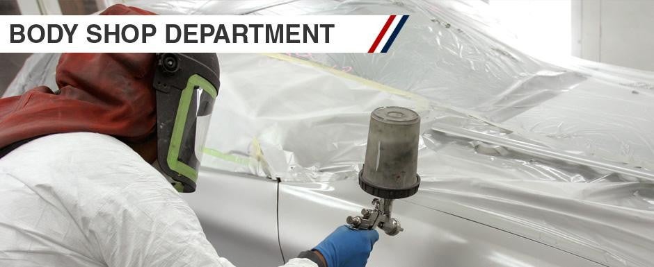 Body shop department spraying a new coat of paint onto a vehicle